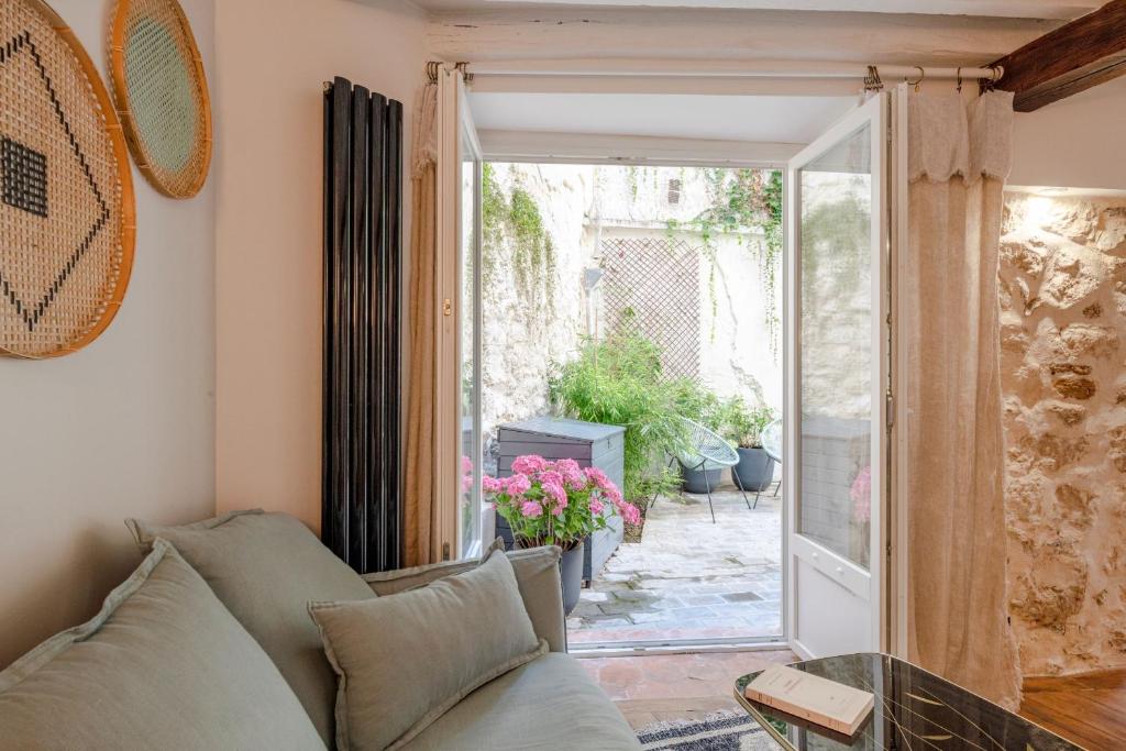 uma sala de estar com um sofá e uma porta de vidro deslizante em Boutik Boheme Le jardin Montmartre em Paris