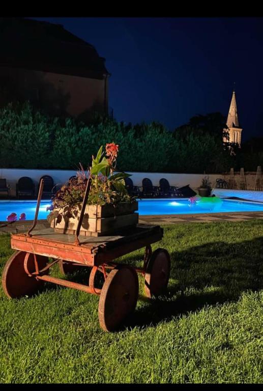 une brouette avec une plante en pot sur l'herbe dans l'établissement la maison porte bonheur, à Chantelle