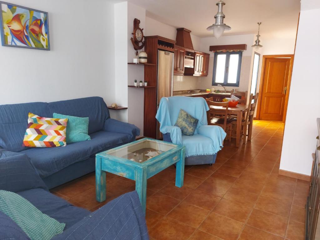 カレタ・デ・ファマラにあるCasa la Caletaのリビングルーム(青いソファ、テーブル付)
