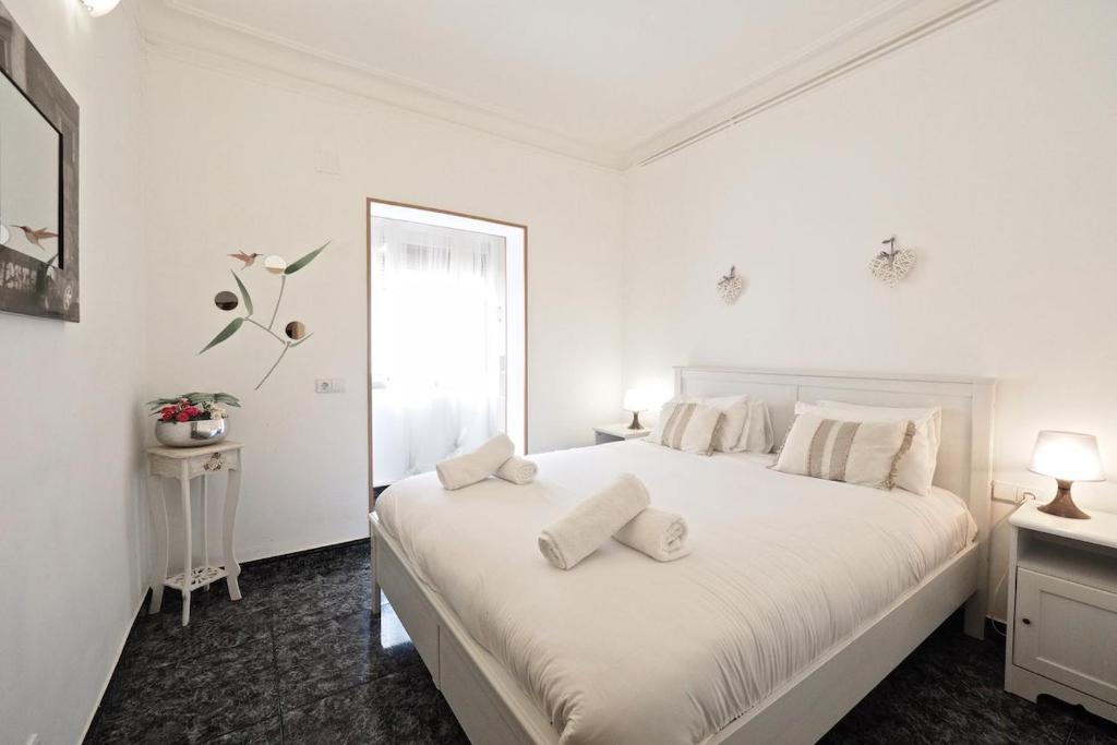 a white bedroom with a large white bed with two pillows at Stay U-nique Apartments Tapioles in Barcelona