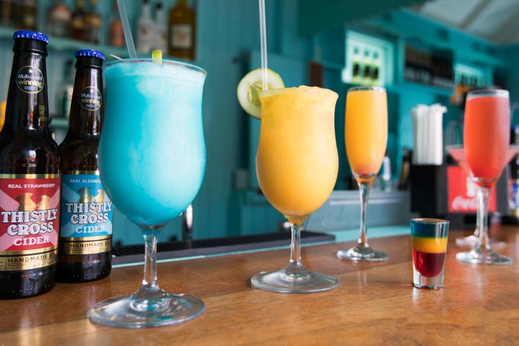 four drinks sitting on a bar with bottles of beer at Sugar Bay Barbados - All Inclusive in Bridgetown