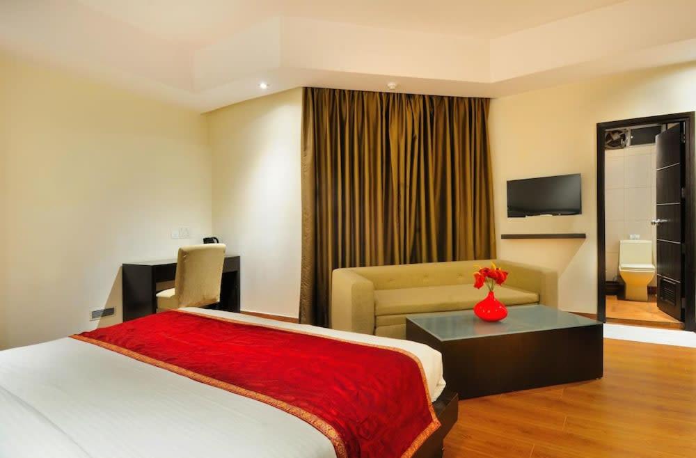 um quarto de hotel com uma cama e um sofá em Zenith Hotel - Delhi Airport em Nova Deli