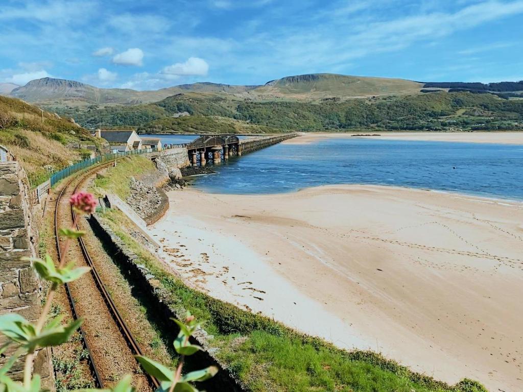 a beach with a train track next to the ocean at No6 in Barmouth