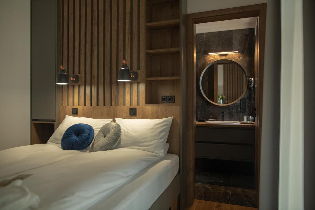 1 dormitorio con cama con espejo y lavamanos en Tahiti Resort Apartments Hajdúszoboszló en Hajdúszoboszló