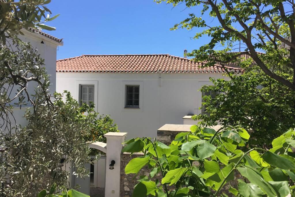 una casa blanca con una puerta y árboles en Relax & Enjoy, en Spetses