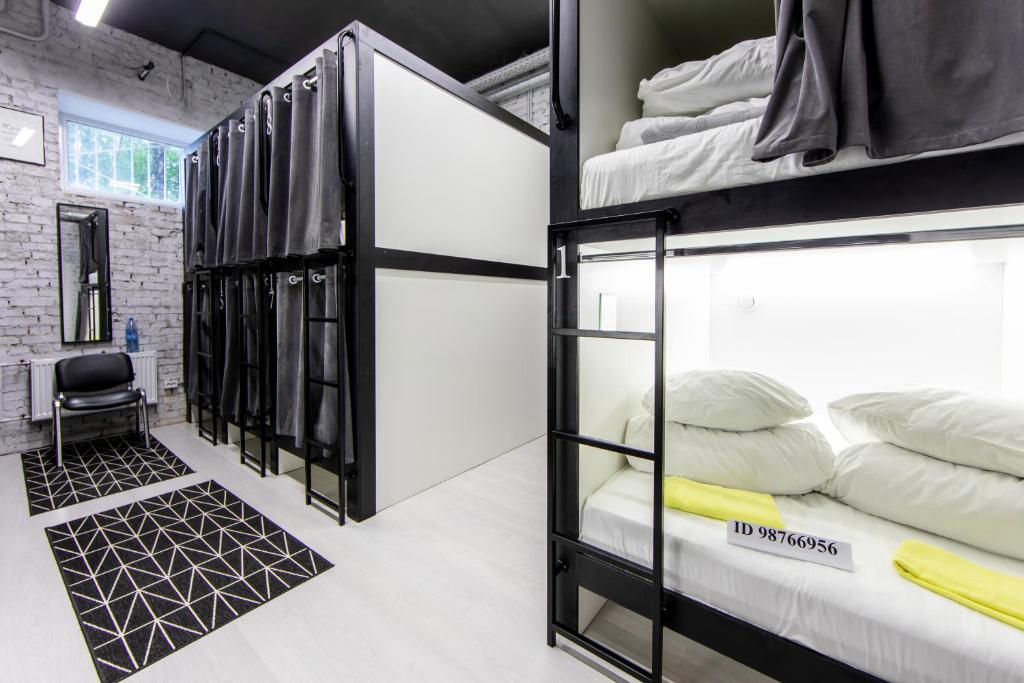 a room with bunk beds in a room with a desk at Atmosphere Capsule Hostel in Tyumen