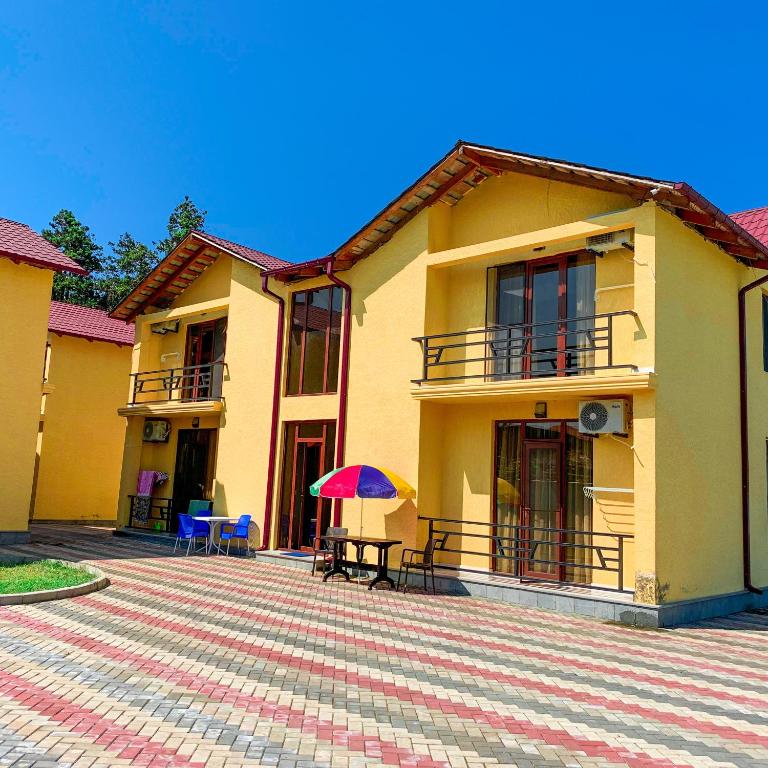 a yellow house with a table and a purple umbrella at Royal Cottage in Ureki