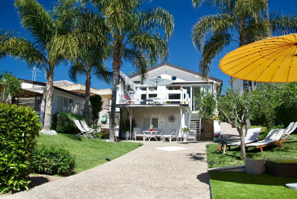 a house with palm trees and a yellow umbrella at Villa Volli Three Rooms in Agrigento