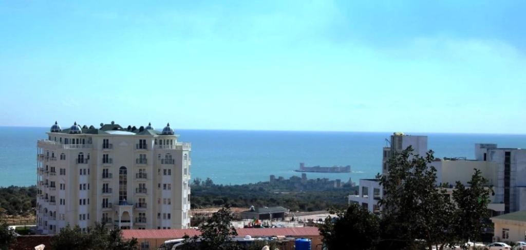 a large building in a city with the ocean in the background at Watercastle Suites in Erdemli