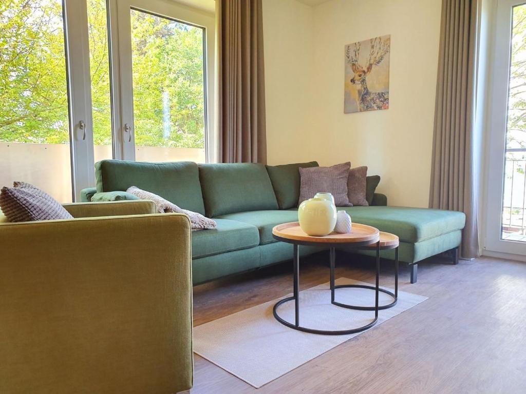 un soggiorno con divano verde e tavolo di Kapitänshaus 3 a Kellenhusen