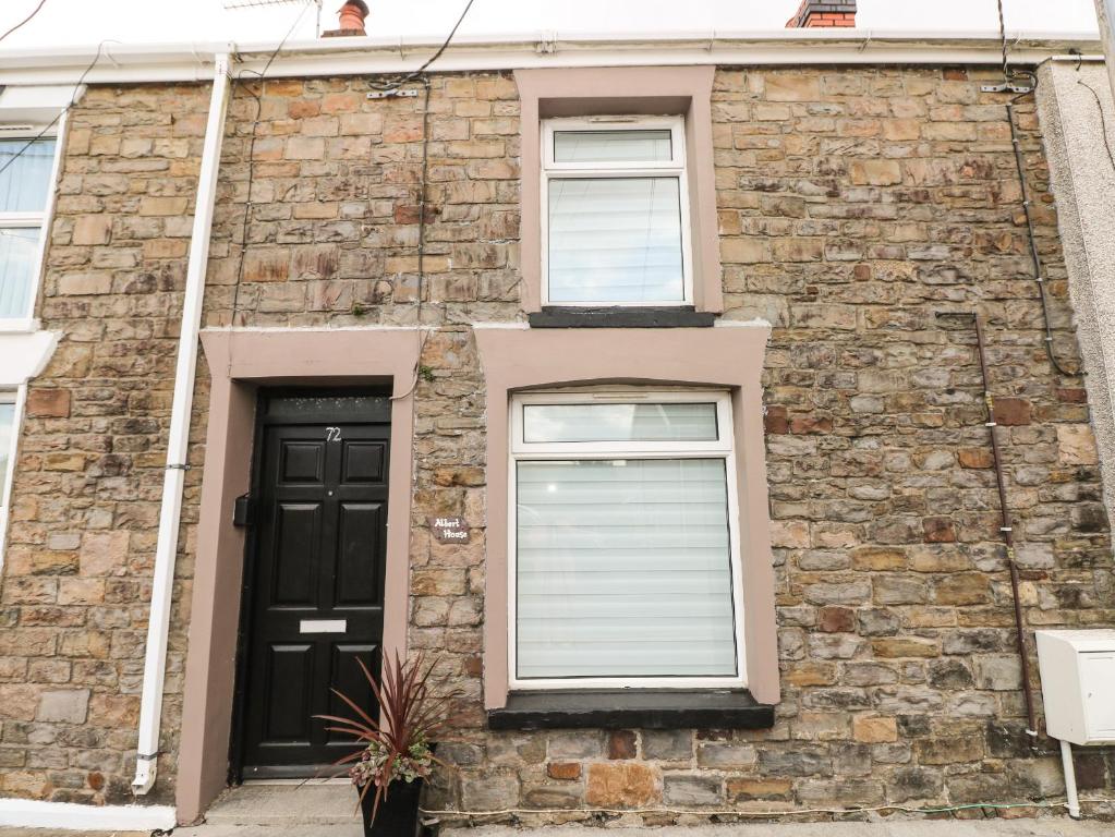 a brick house with two windows and a black door at Albert House in Ammanford