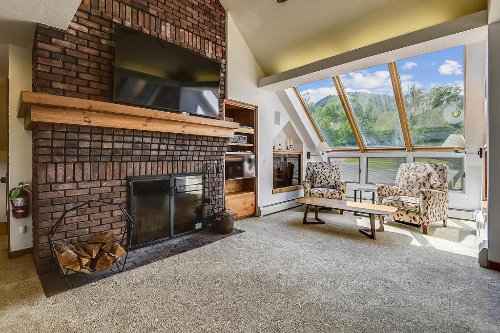 a living room with a brick fireplace with a tv at Sunrise Timberline C1 in Killington