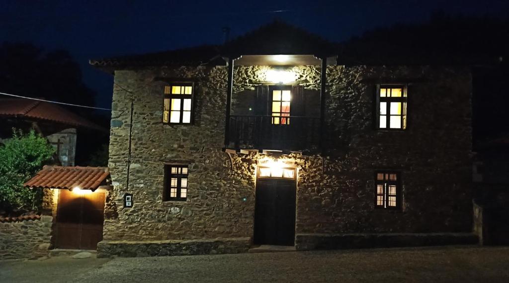 a stone house with a balcony and a door at night at Lithia s Stonehouse. Το πέτρινο στη Λιθιά - Καστοριά in Lithiá