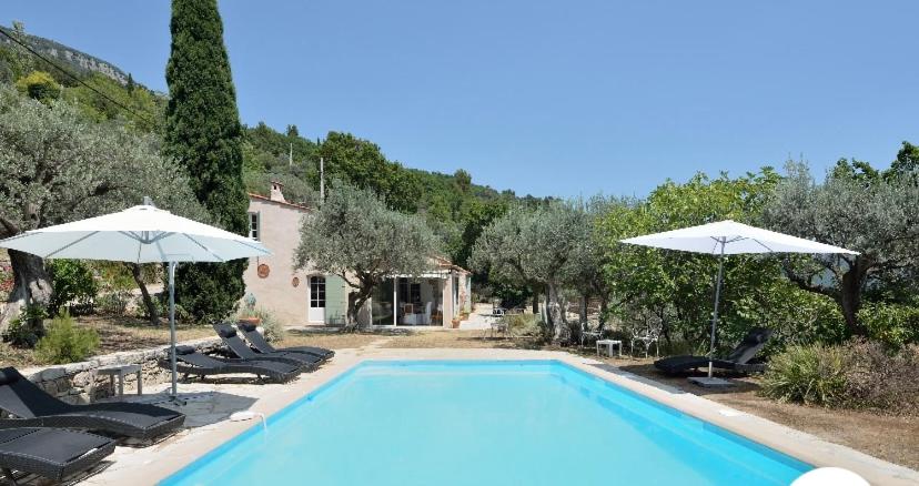 a swimming pool with umbrellas and chairs and a house at romantique villa provencale in Bargemon