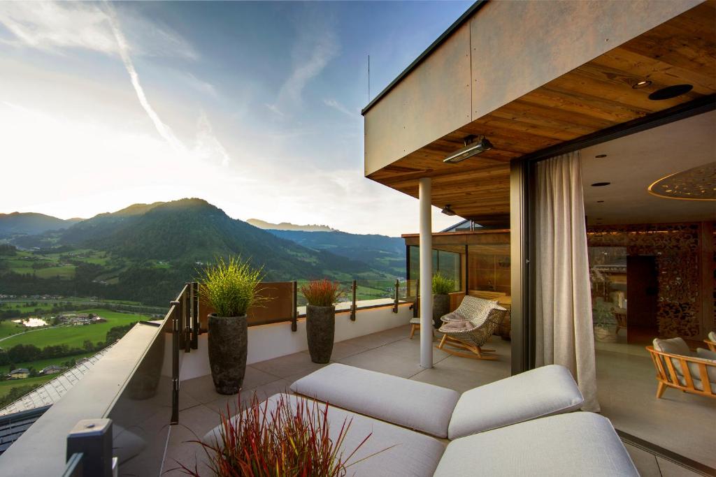 uma varanda com um sofá e vista para uma montanha em Aktivhotel Alpendorf em Sankt Johann im Pongau