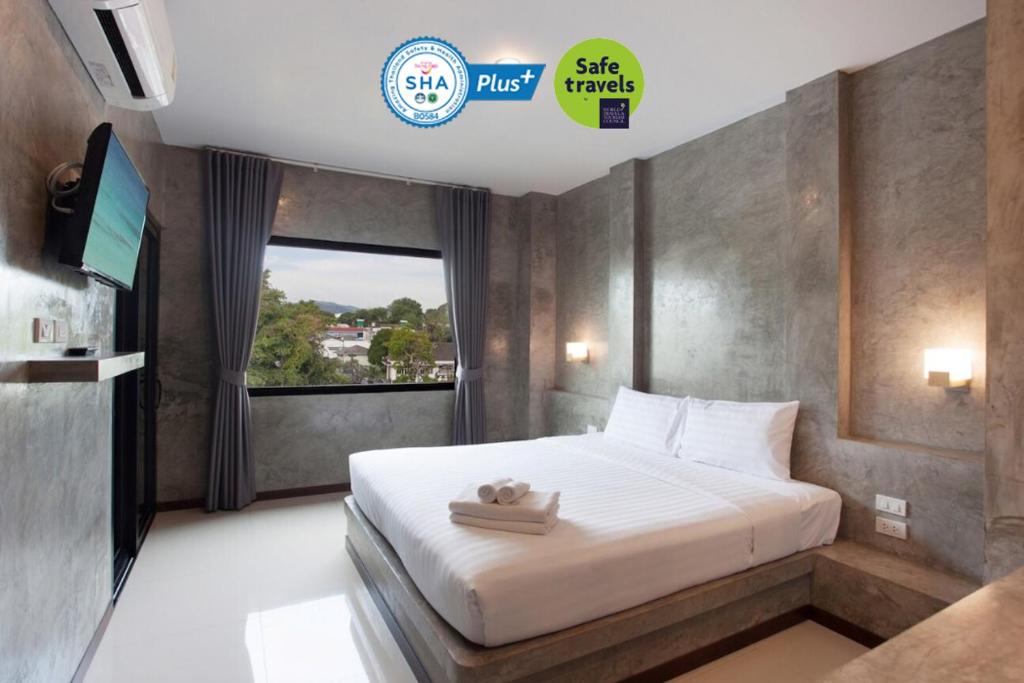 1 dormitorio con 1 cama, TV y ventana en Ritsurin Boutique Hotel - โรงแรมริทสุริน บูติค, en Phuket