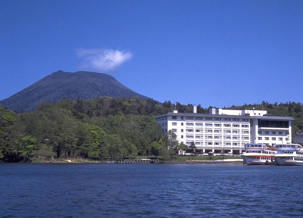 a large building on the water with a mountain in the background at Hotel Akankoso in Akankohan