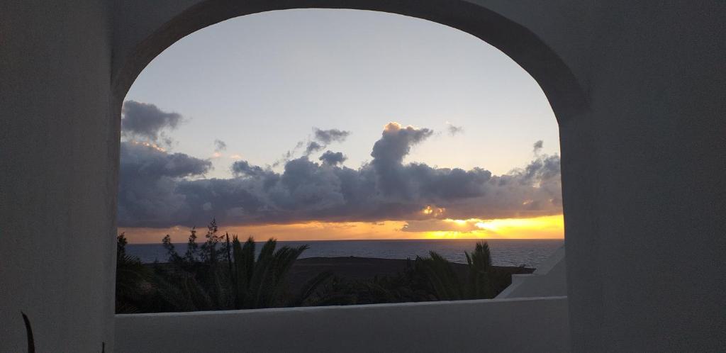 een gewelfd raam met uitzicht op de zonsondergang bij Home sweet home in Costa de Antigua