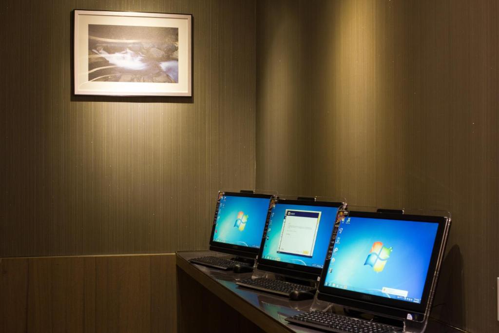 three computer screens sitting on a desk in a room at Royal Guest Hotel in Tainan