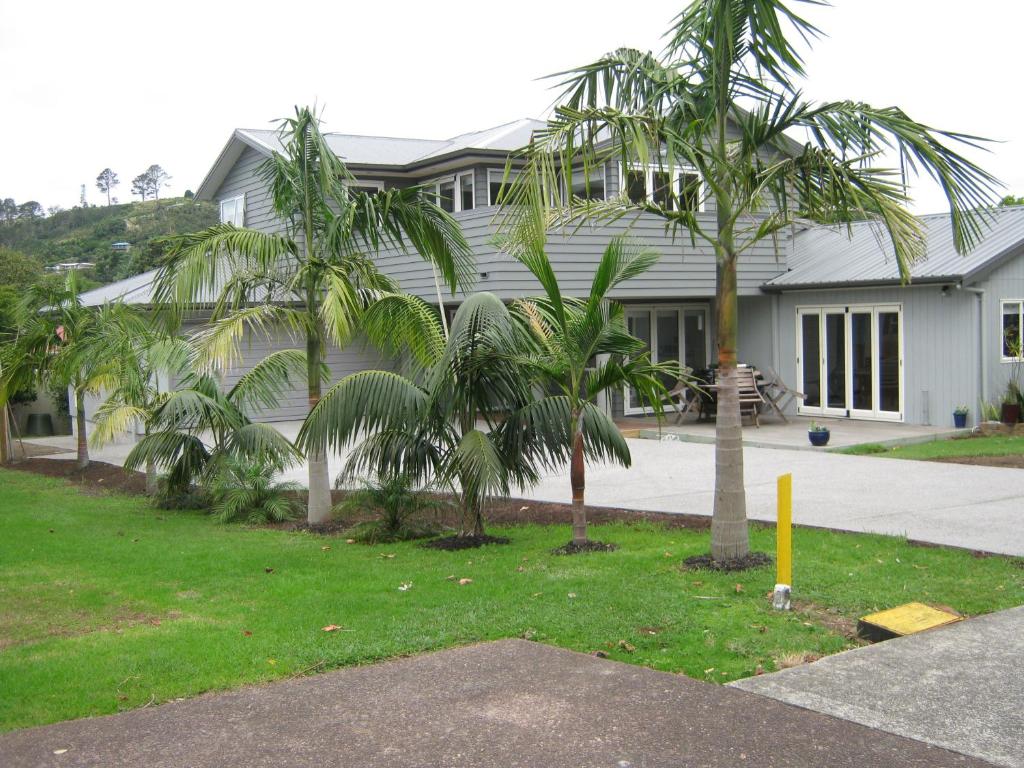 a house with palm trees in front of it at Cathedral Cove Apartment in Hahei