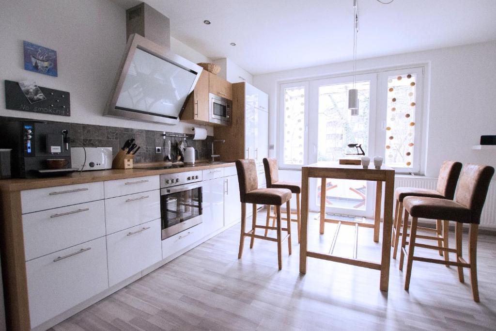 eine Küche mit weißen Schränken sowie einem Tisch und Stühlen in der Unterkunft Apartment Hannover Top Citylage in Hannover