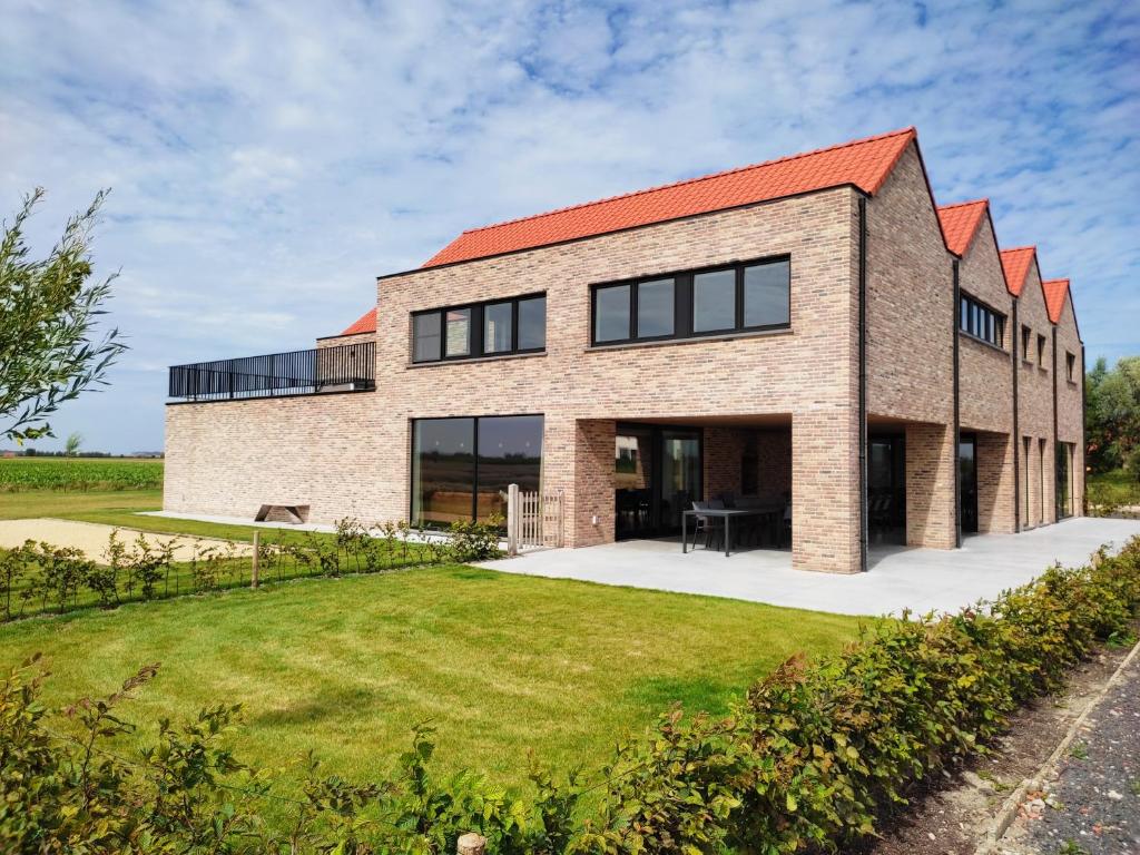 a brick house with a red roof at De Balloo, vakantiehuis met sauna en jacuzzi in Zuienkerke