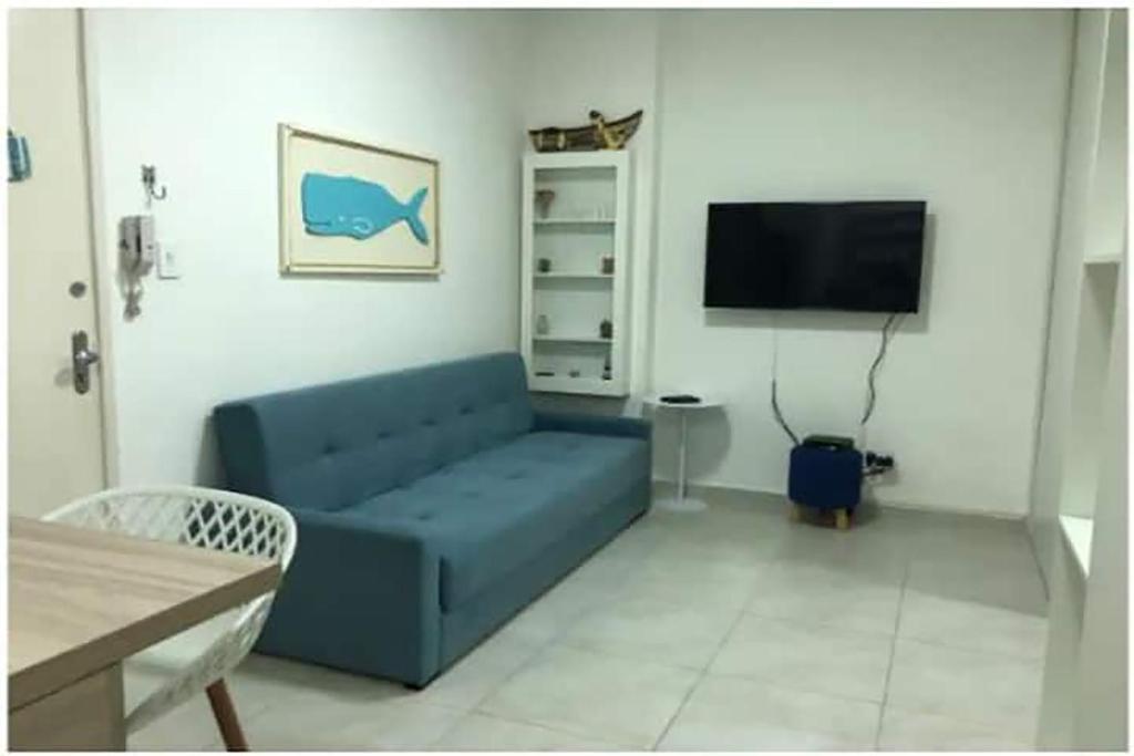 a living room with a blue couch and a tv at Apto com Wi-Fi bem perto da praia em Santos SP in Santos