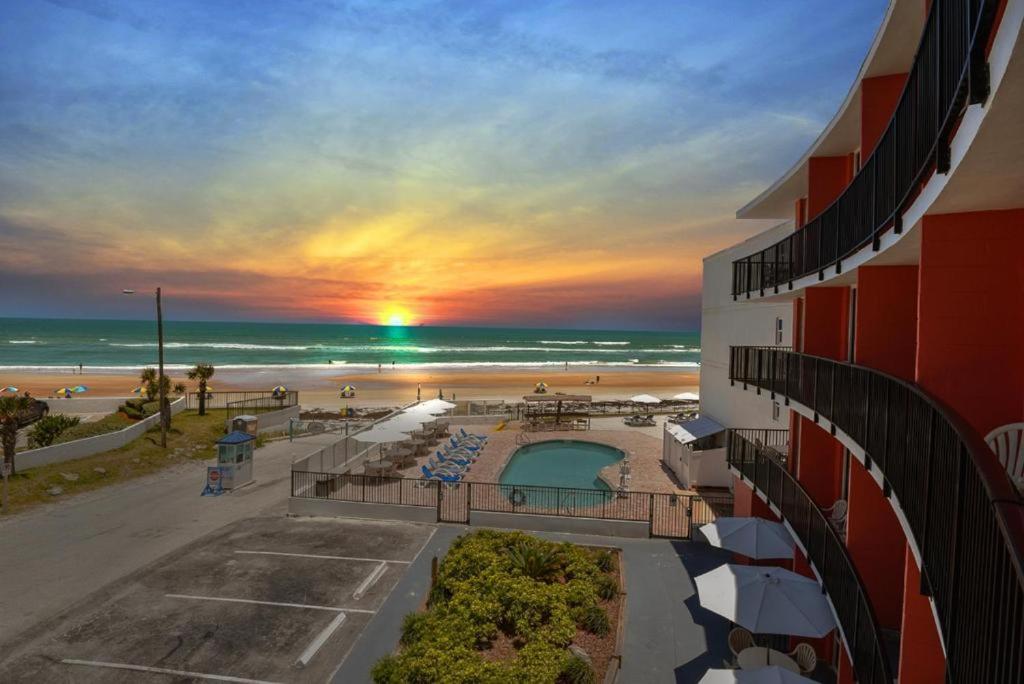 a view of a beach and a hotel with a sunset at Cove Motel Oceanfront in Daytona Beach