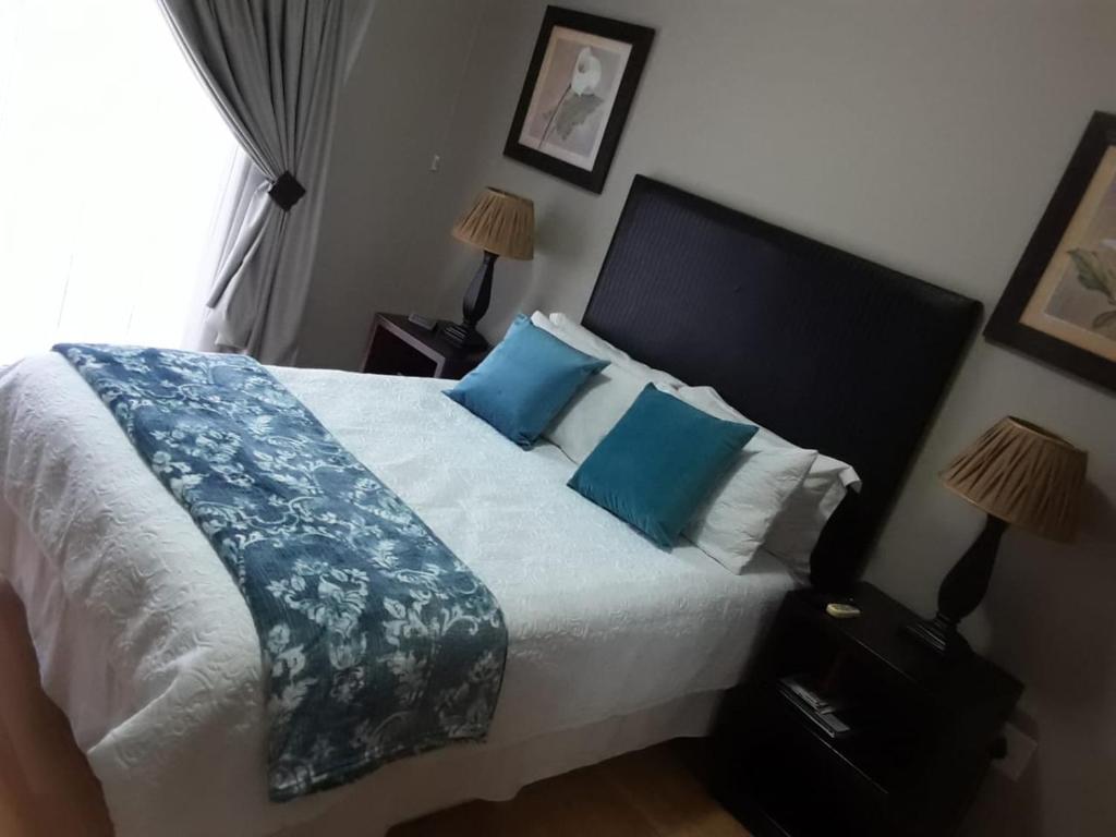 um quarto com uma cama grande e almofadas azuis em Nimza K Guesthouse em Kimberley