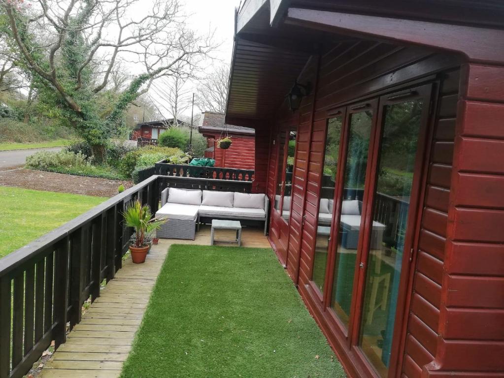 - une terrasse couverte avec un canapé et une pelouse dans l'établissement Wooden Forest Lodge by the sea, à Milford on Sea