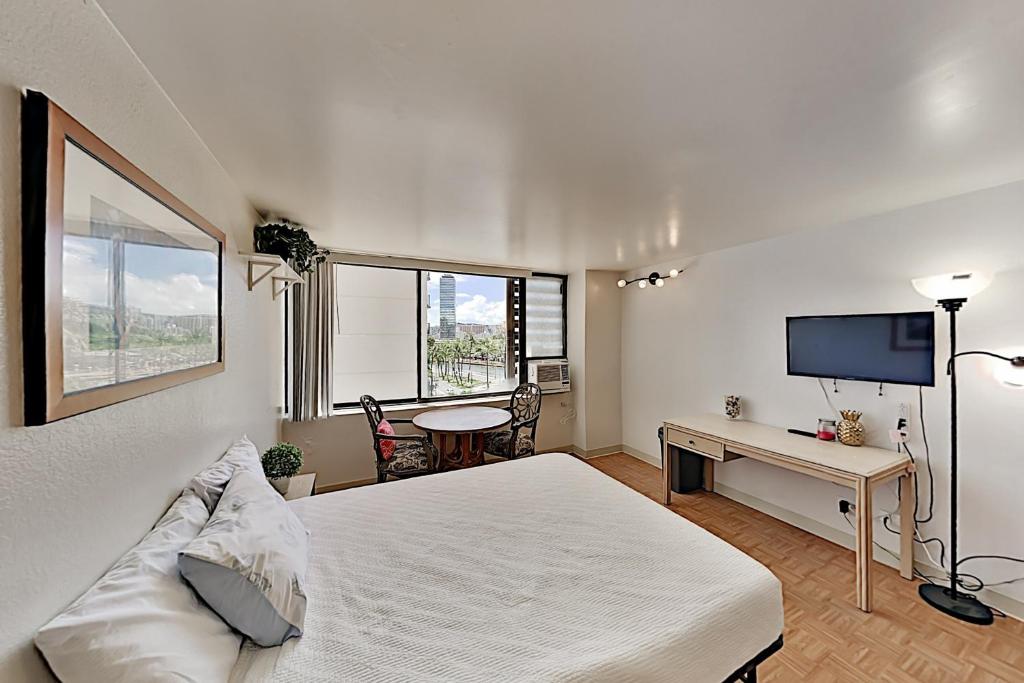 een slaapkamer met een bed, een bureau en een televisie bij Hawaiian Monarch 801 condo in Honolulu