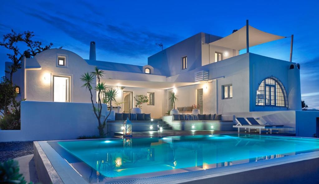 a villa with a swimming pool at night at Aleria Villa Santorini in Mesaria