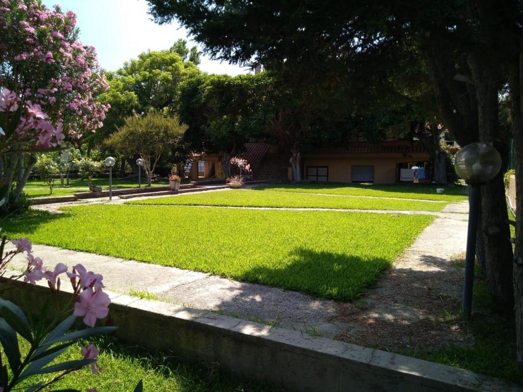 un jardin avec une maison en arrière-plan dans l'établissement Seafront, à San Sostene Marina