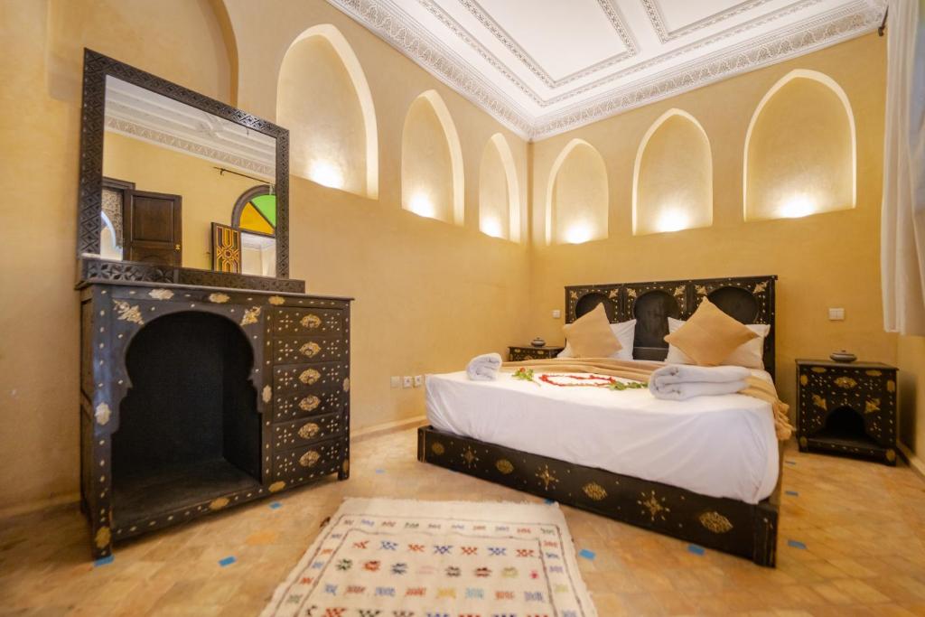 a bedroom with a bed with a fireplace and a mirror at Riad Full Moon in Marrakesh
