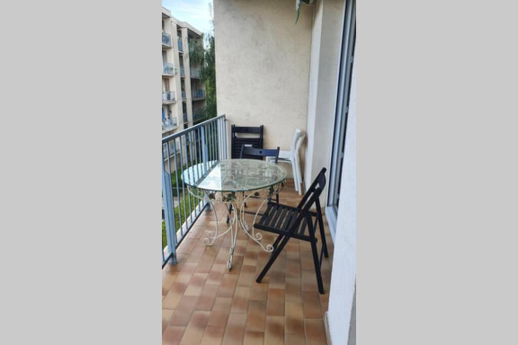 een balkon met een glazen tafel en stoelen erop bij Near to Paris Evry courcouronne terrasse in Évry-les-Châteaux