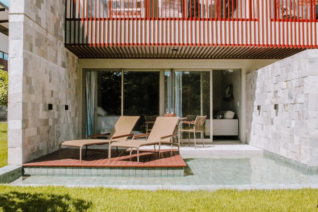 eine Terrasse mit Stühlen und einem Tisch in einem Haus in der Unterkunft Qavi - Flat completo com piscina privativa #ÎledePipa in Pipa
