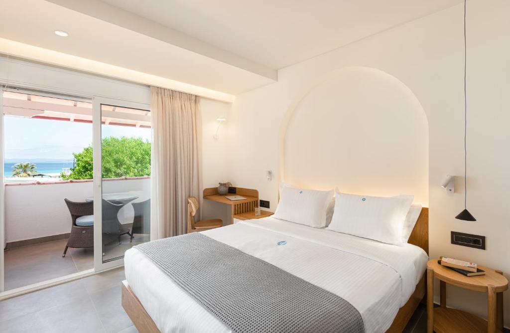 a bedroom with a bed and a view of the ocean at Antigoni Seaside Resort in Ormos Panagias