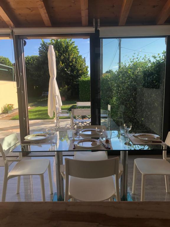 mesa de comedor con sillas blancas y sombrilla en LUXURY vertical open space, en Sangiano