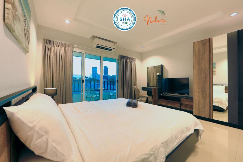 um quarto com uma grande cama branca e uma televisão em Nalanta Hotel Pattaya em Pattaya Central
