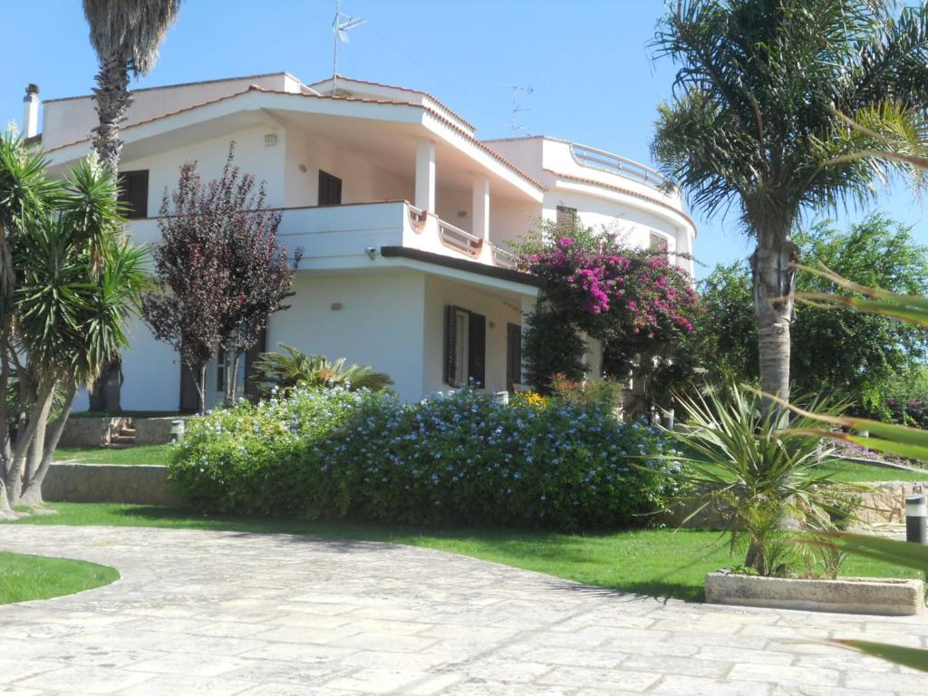 a white house with palm trees and a driveway at Le Schiavelle in Surbo