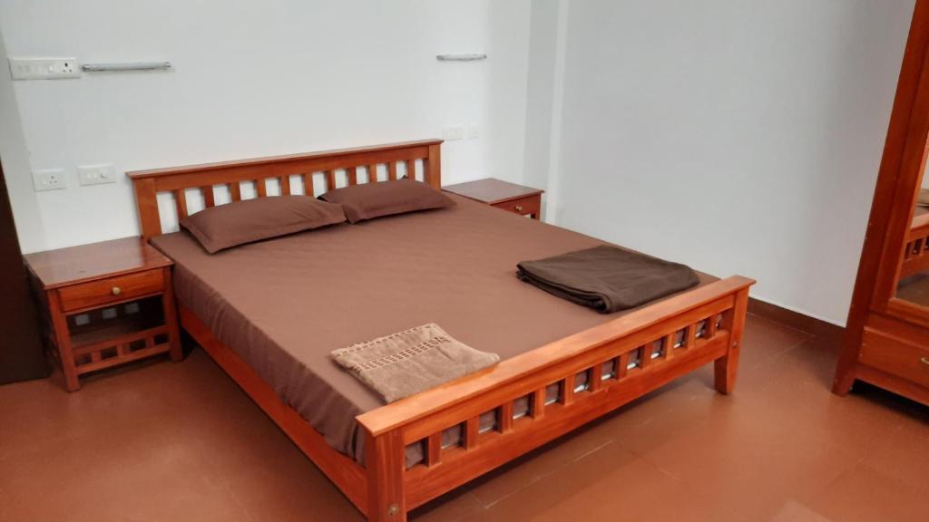 - un lit en bois dans une chambre avec 2 tables de chevet dans l'établissement Poovar Sea View rooms and boating Family & couple only, à Pūvār