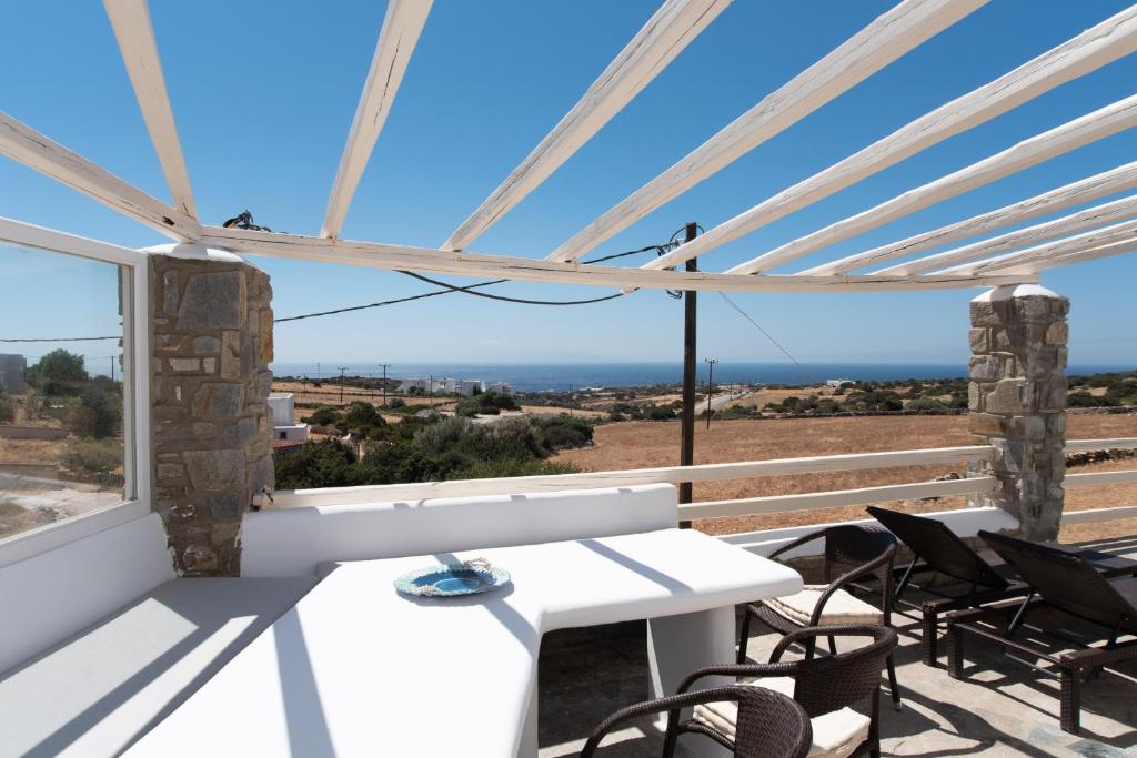 een witte tafel en stoelen op een balkon met uitzicht op de oceaan bij Aspro Paros Villa in Aspro Chorio Paros