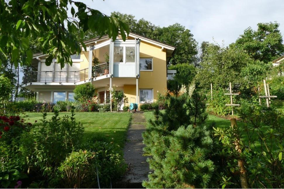 a yellow house with a porch and a yard at Haus Annette in Weisweil