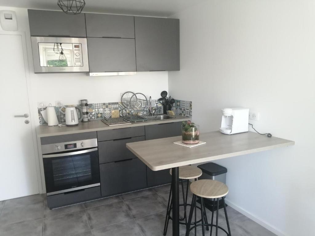 a kitchen with gray cabinets and a counter with stools at Appartement T2 indépendant avec terrasse et parking gratuit - Proche palais des congrès-Baie de Saint-Brieuc in Ploufragan