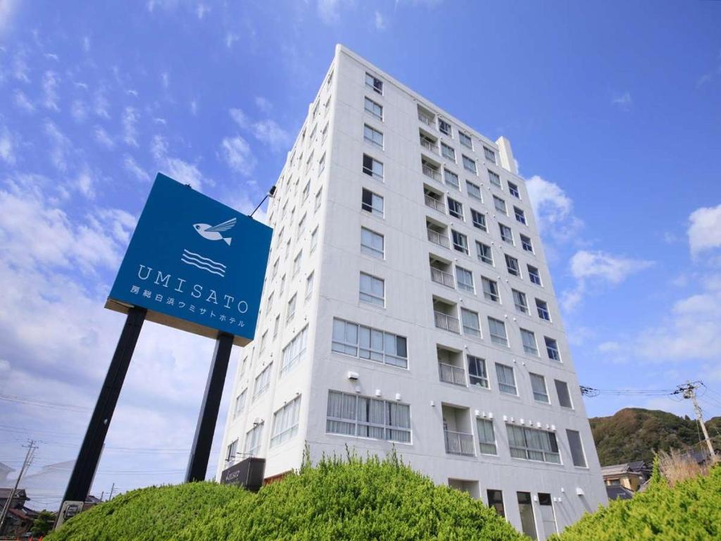 a white building with a blue sign in front of it at Boso Shirahama Umisato Hotel in Minamiboso