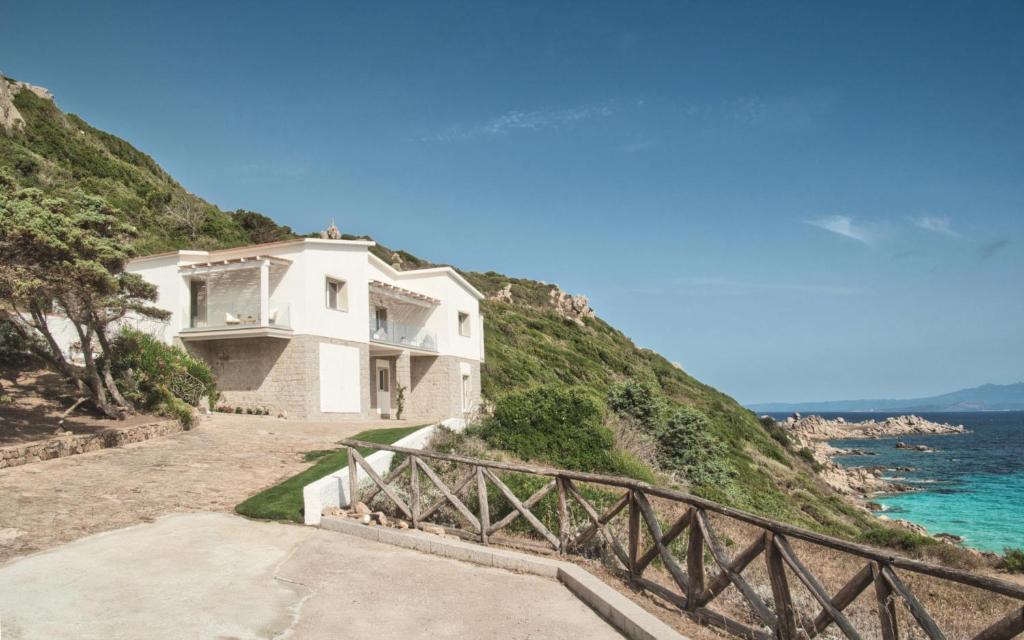 a white house on a hill next to the ocean at Villa Bianca Luxury B&B Experience in Santa Teresa Gallura