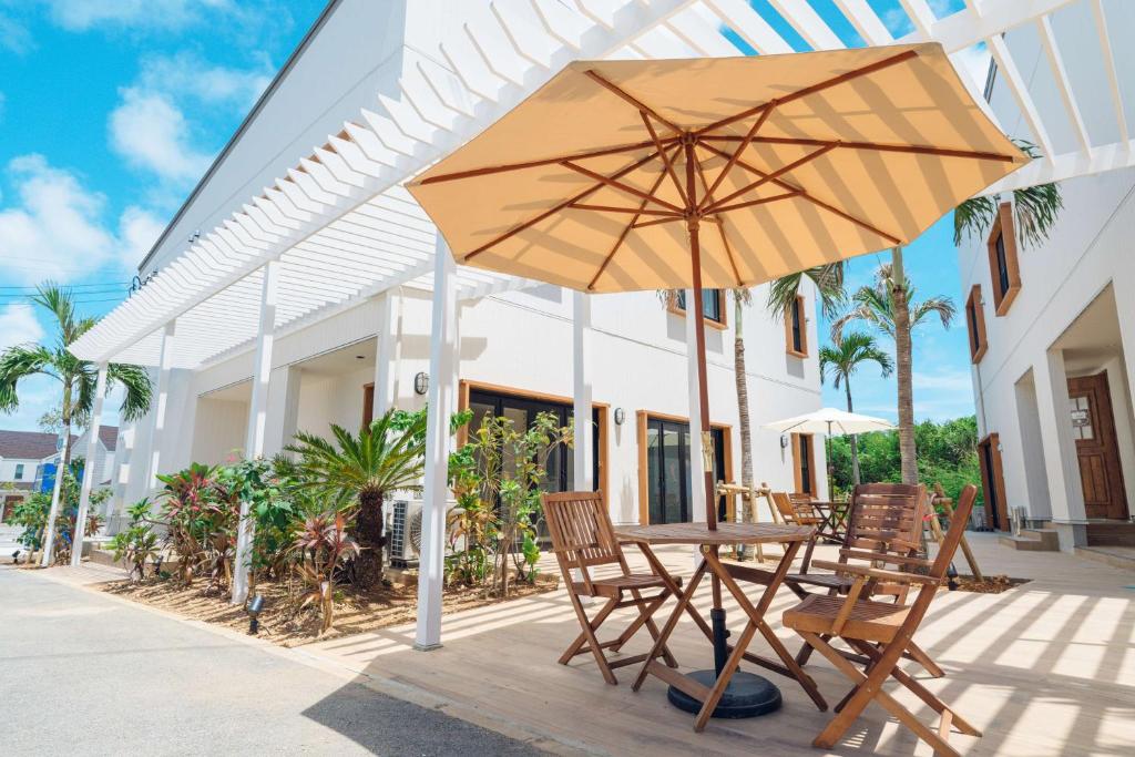 een tafel en stoelen en een parasol op een patio bij Hotel California Miyakojima Resort in Miyako Island