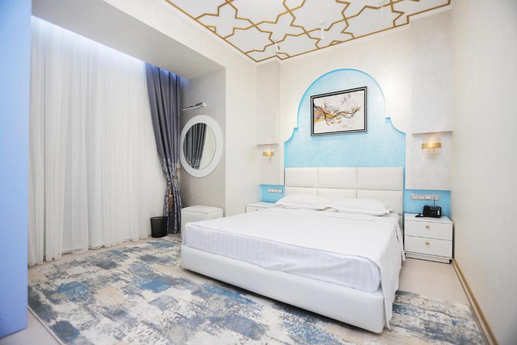 1 dormitorio con 1 cama blanca y paredes azules en Reikartz Amirun Tashkent, en Tashkent