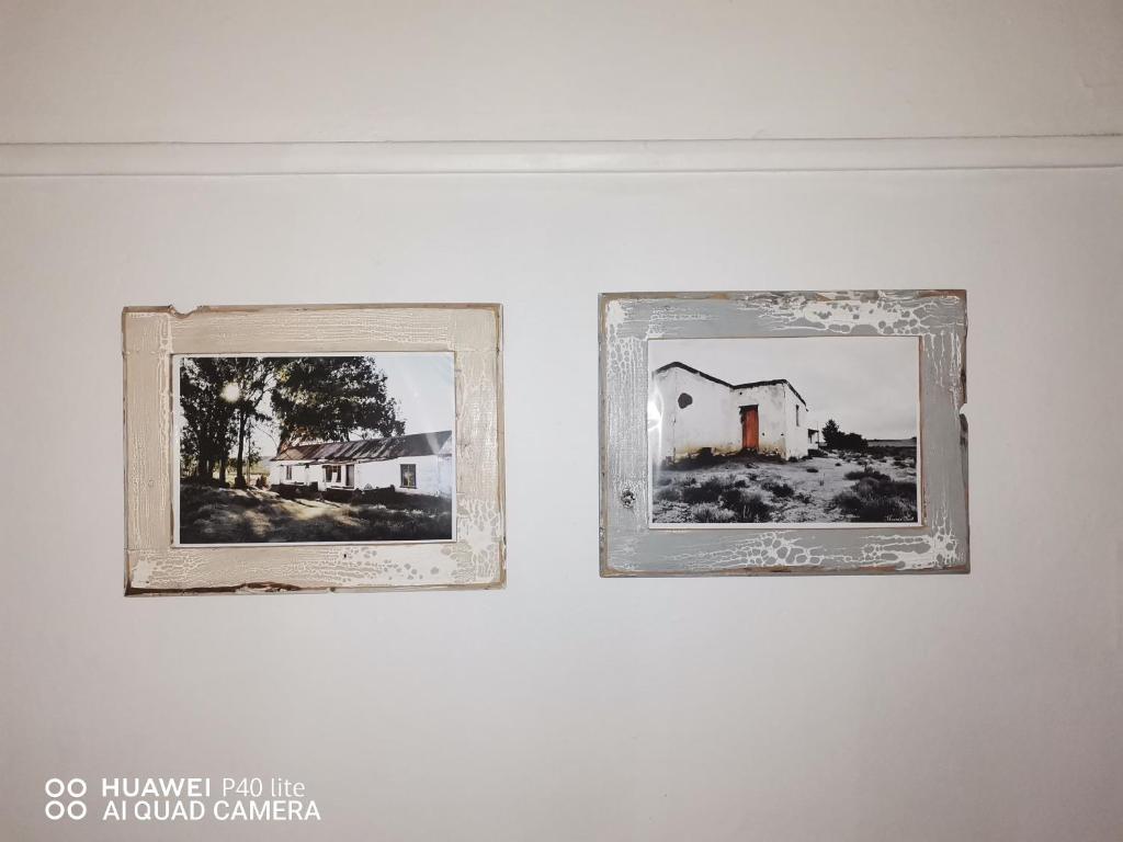 two framed pictures of a house on a wall at Bird Haven Guesthouse in Leribe
