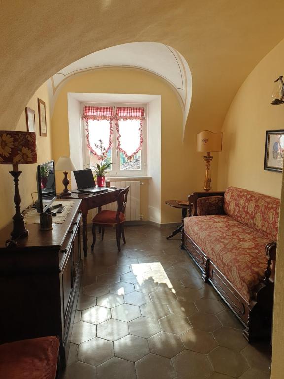 salon z kanapą i biurkiem z laptopem w obiekcie La Foresteria del Passeggere w mieście Ovada
